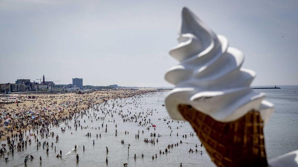 people at beach and giant ice cream cone. 