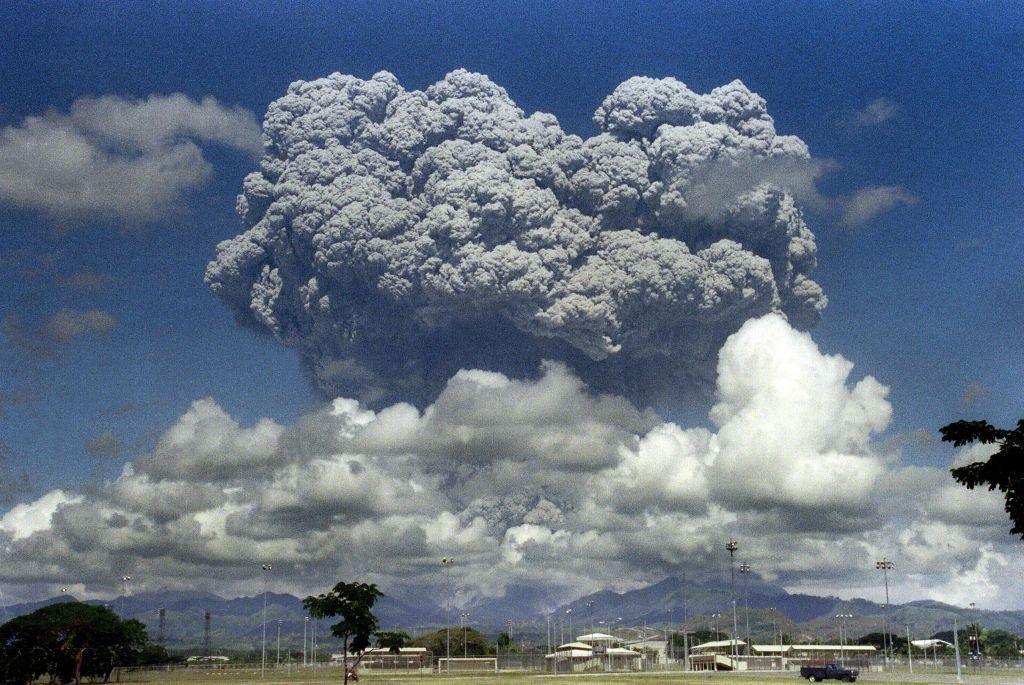 Ash cloud from Mount Pinatubo erupting, rising high into sky above clouds