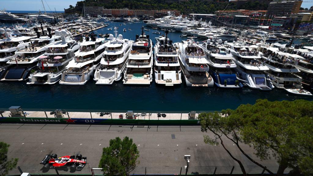 Ferrari's Lewis Hamilton drives past the harbour in Monaco with luxury yachts in the background