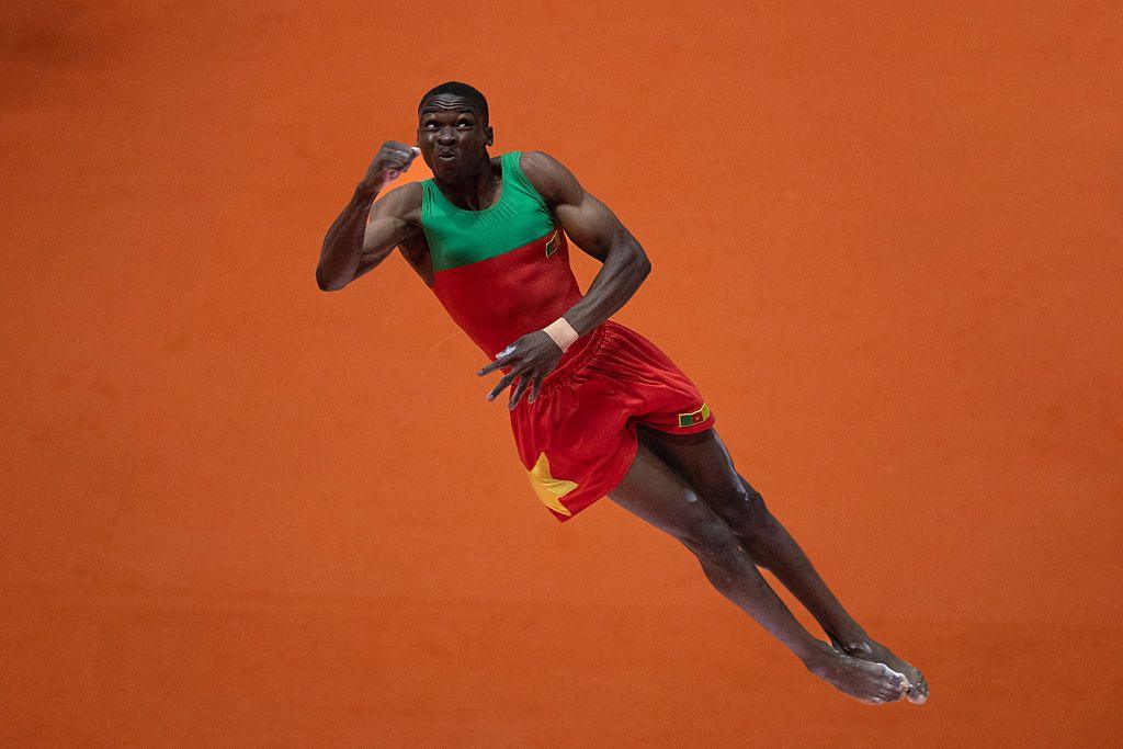 A man leaps into the air during a vault routine.