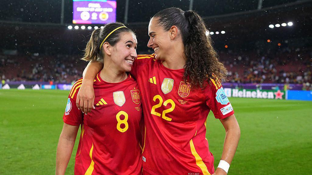 two spanish players hugging in their red kits