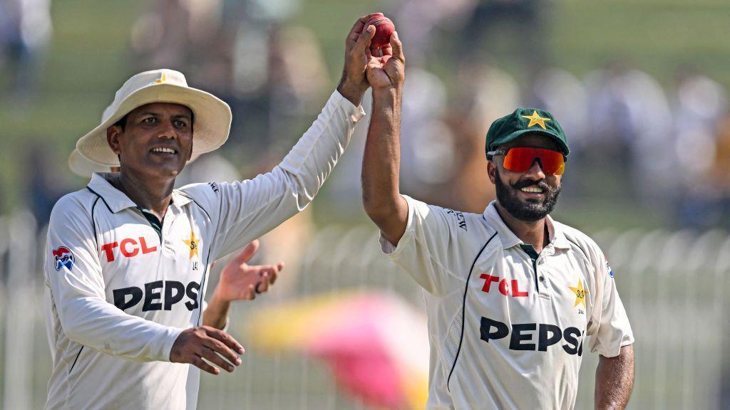 Pakistan spinners Noman Ali (left) and Sajid Khan (right) hold up the ball together as they walk off after dismissing England