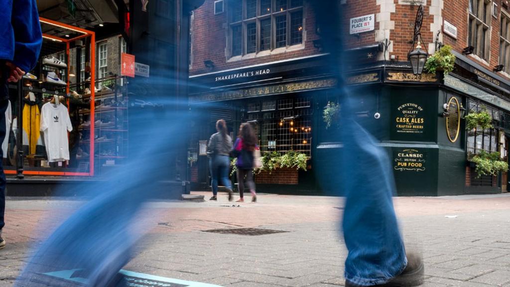 Man walks in street outside pub