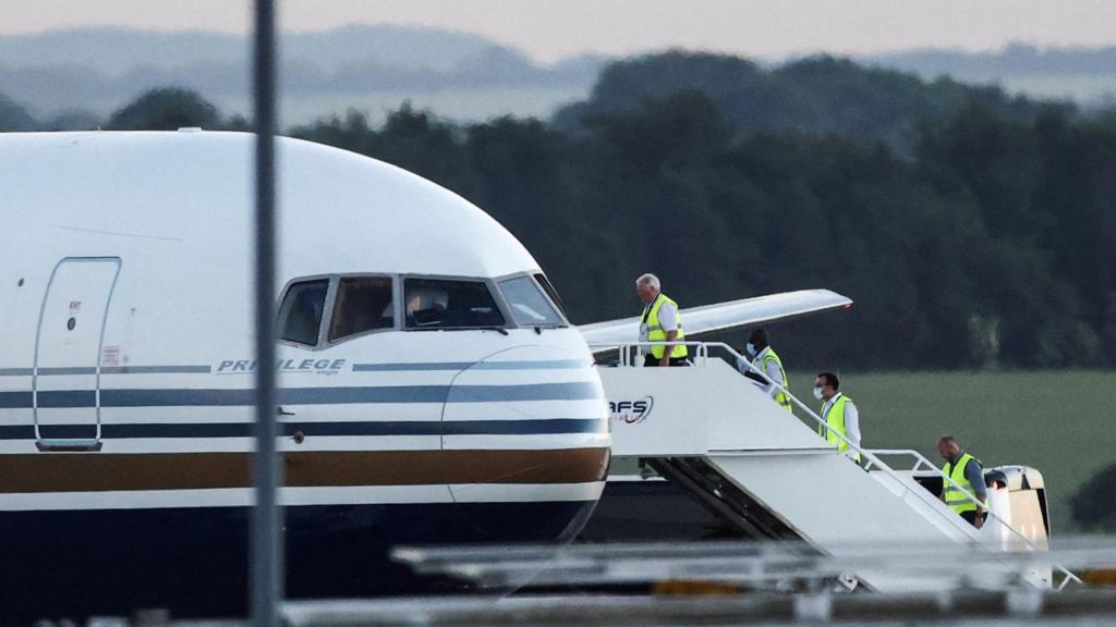 Members of the staff board a plane reported by British media to be first to transport migrants to Rwanda