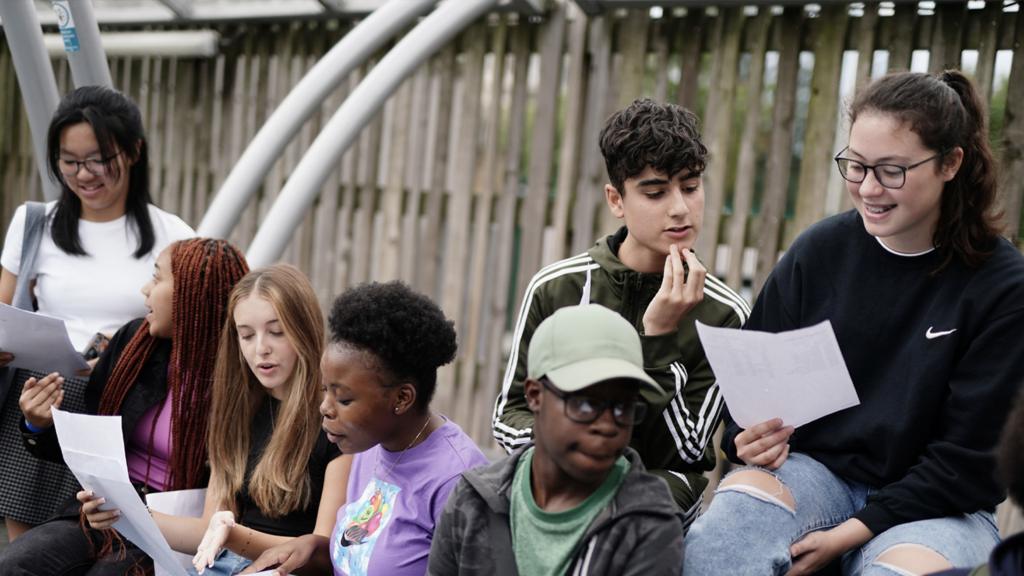 A group of young people looking at papers as they receive their GCSE results