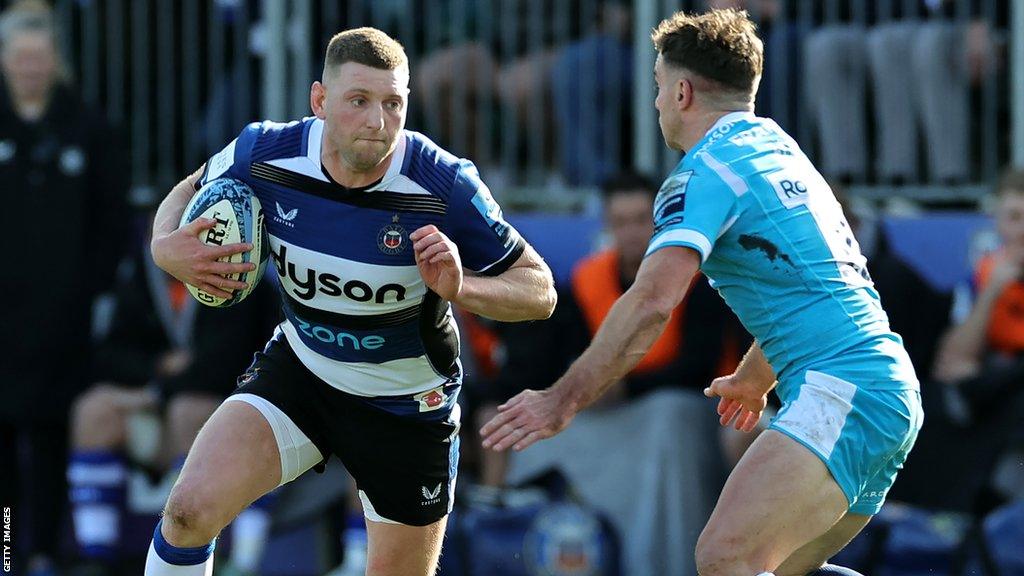 Finn Russell with the ball evades a tackle from George Ford