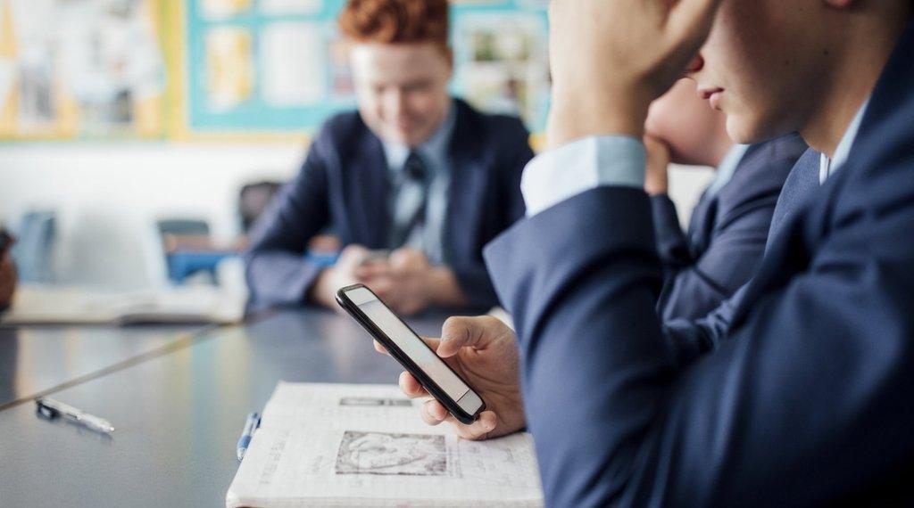 Pupils using their mobile phones in a classroom