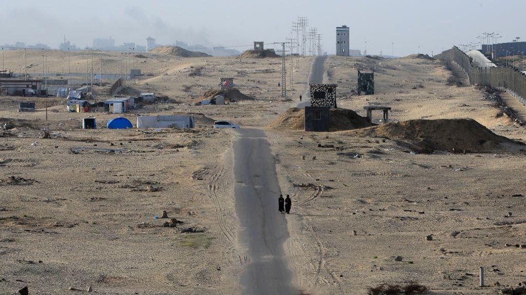 Palestinian women walk along a road in the Philadelphi Corridor, which runs along the Gaza-Egypt border south of Rafah (22 May 2024)