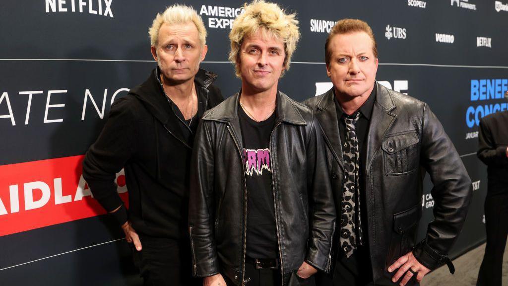 The members of Green Day pose on a carpet before the FireAid benefit concert 