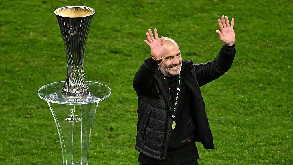 Enzo Maresca waves to Chelsea fans, as he walks past the Conference League trophy