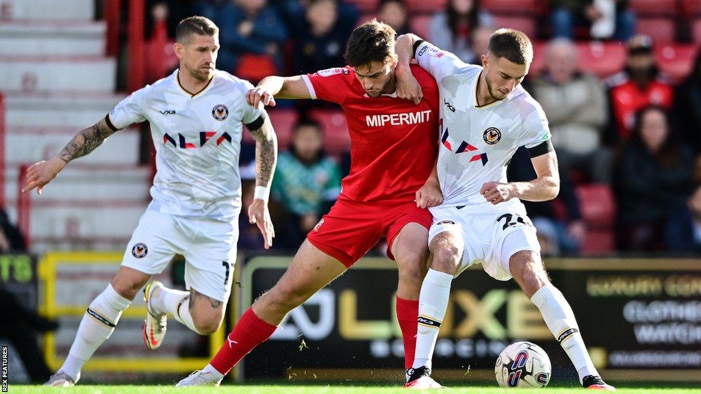 Jake Young of Swindon Town battles for the ball with Matthew Baker of Newport County