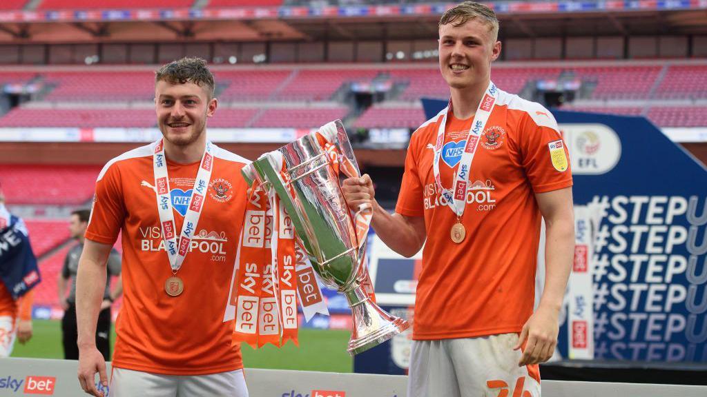 Elliot Embleton celebrates with the League One play-off winners' trophy at Wembley in 2021