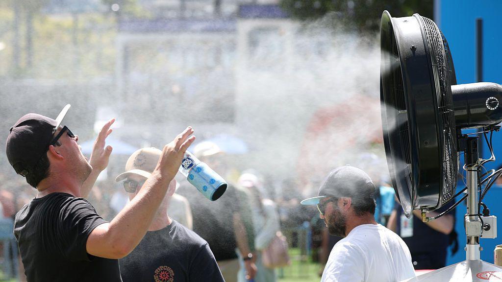A man stands in front of a water mister in Melbourne Park