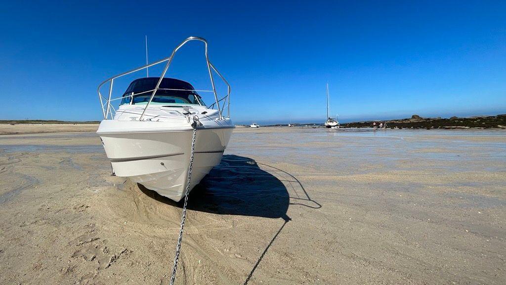 A modern white boat tied up on a sandy beach.