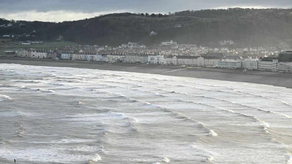 Tonnau'n rholio i'r traeth yn Llandudno yng ngogledd Cymru ar 8 Rhagfyr 2024