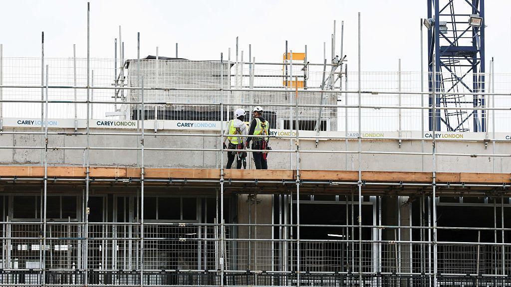 Workers are seen on a construction site in London, where a tower block is underway.
