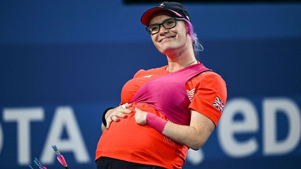 Jodie Grinham of Great Britain holds her pregnancy bump after winning her women's individual compound open bronze medal match against Phoebe Paterson Pine of Great Britain on day three of the Paris 2024 Paralympic Games 