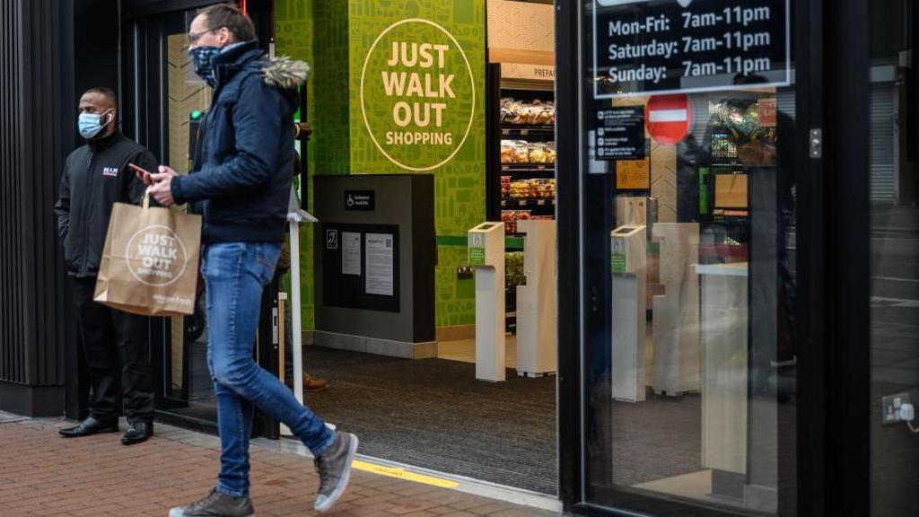 A shopper walking out of an Amazon Fresh store in London in 2021