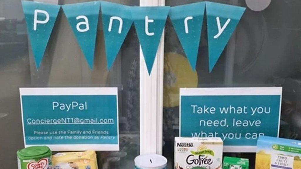 The CommunitEE Pantry table with assorted food staples and signs saying to take what you need and leave what you can