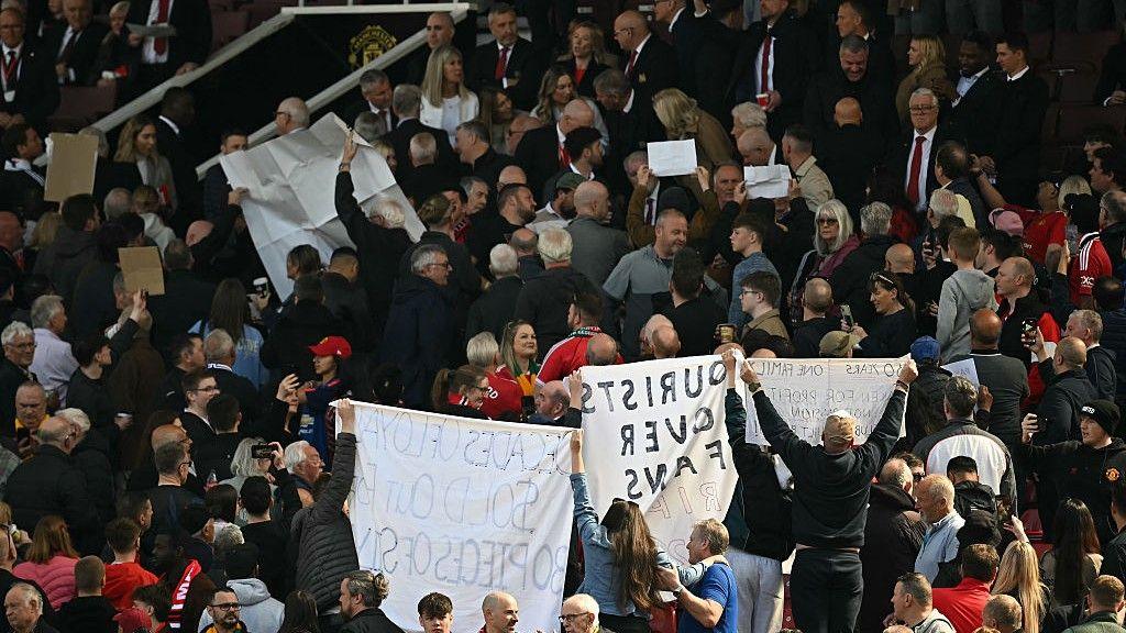 Manchester United fans holding banners up towards the directors' box at Old Trafford in April 2025 in protest at being moved from their seats