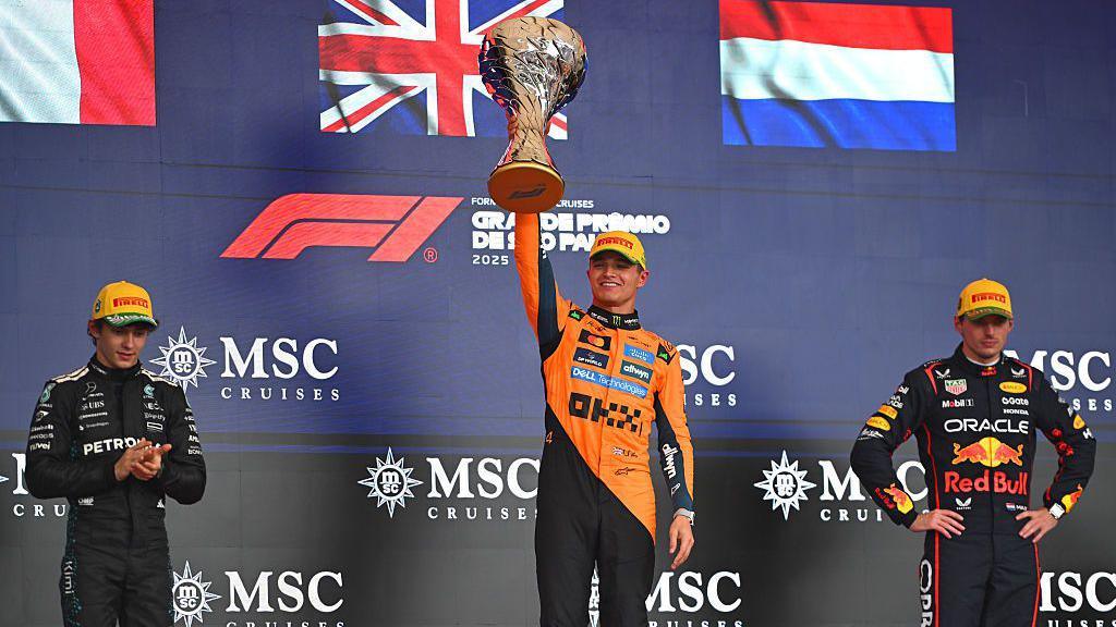 Lando Norris lifts his winner's trophy on the podium in Sao Paulo 