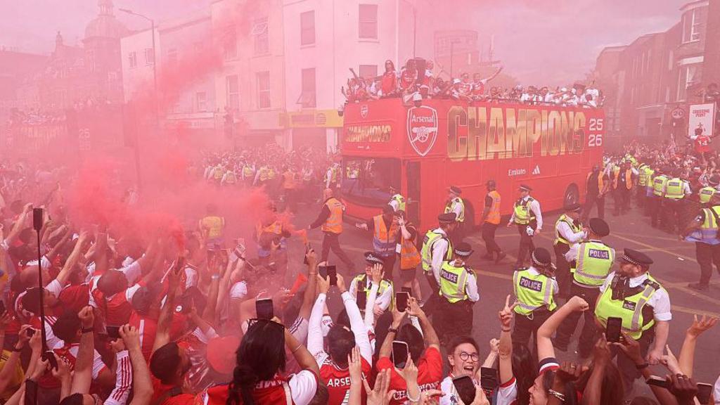 Arsenal's women's team players celebrate with their FIFA Women's Champions Cup trophy during a victory parade with the men's team around the streets near to the Emirates Stadium, in London, 