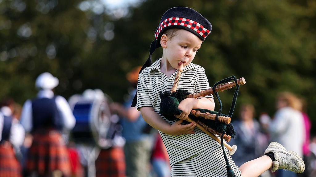 An attendee plays with a toy bagpipe