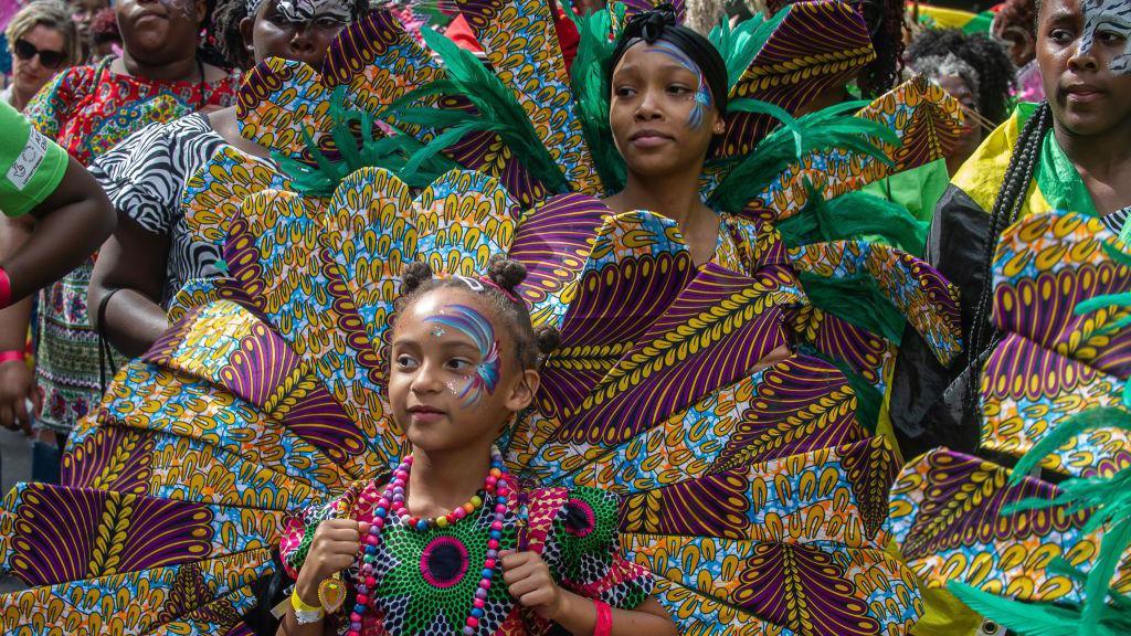 People in colourful outfits at Notting Hill Carnival. 