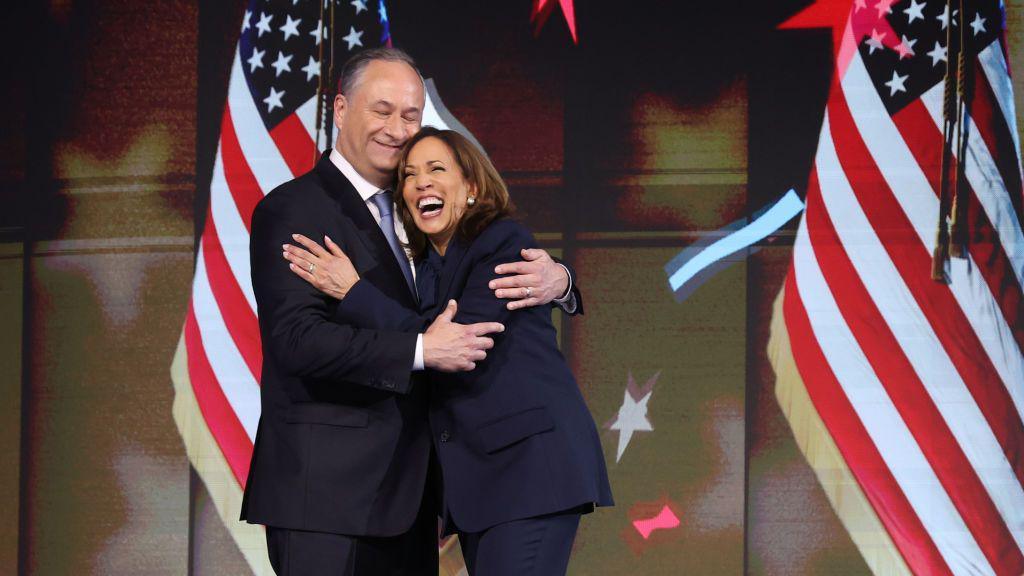 Wearing a dark suit, Kamala Harris embraces her husband Doug Emhoff at the 2024 Democratic convention in Chicago