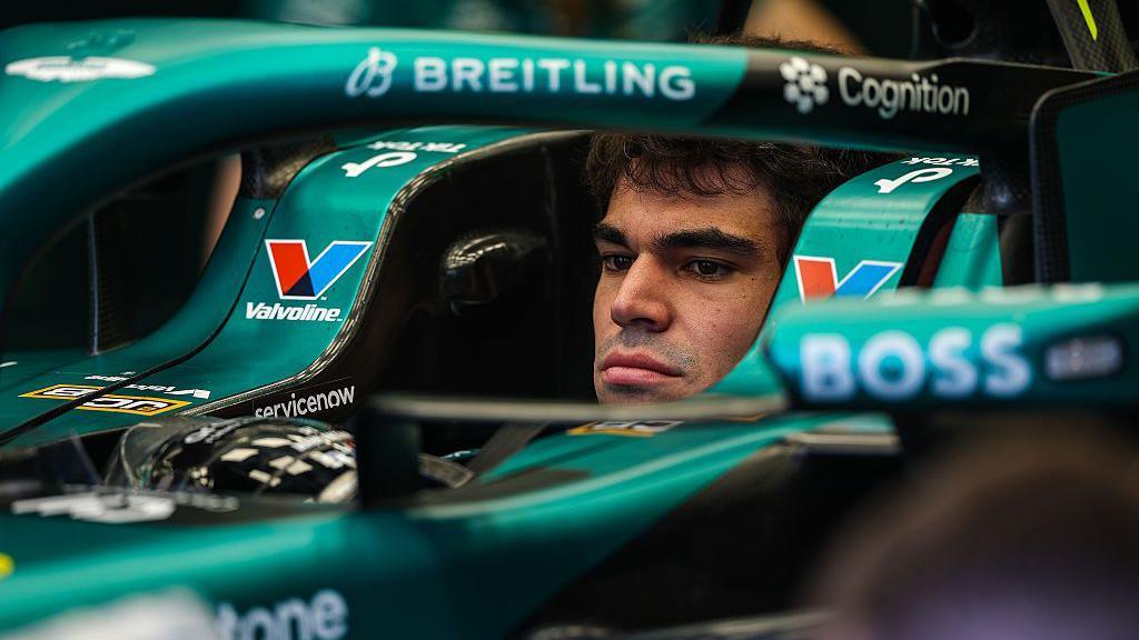 Lance Stroll sits in the Aston Martin car without his race helmet