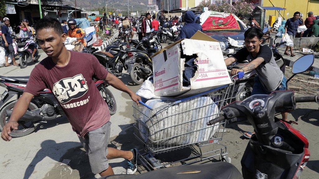 People drag a shopping trolley with goods looted from a supermarket in Palu. Photo: 30 September 2018