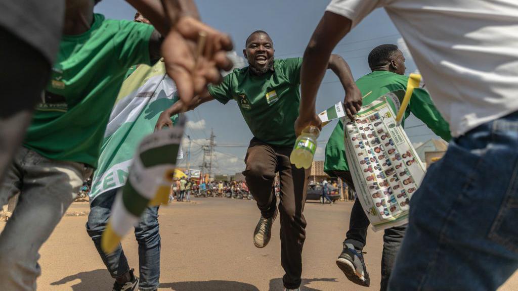 Supporters of the Democratic Green Party dance as they attend the party's political rally in Gihara, Rwanda, on June 23, 2024, ahead of Rwanda's upcoming parliamentary and presidential elections.