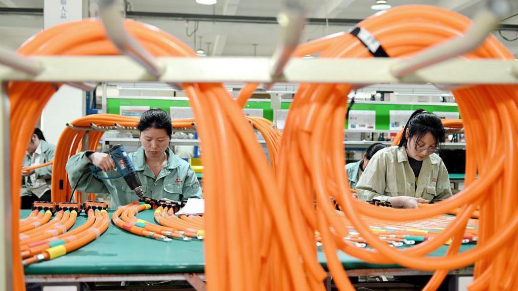Workers manufacture high-voltage wiring harness products for new energy vehicles in the workshop in Nantong City, Jiangsu Province, China, on May 13, 2025.