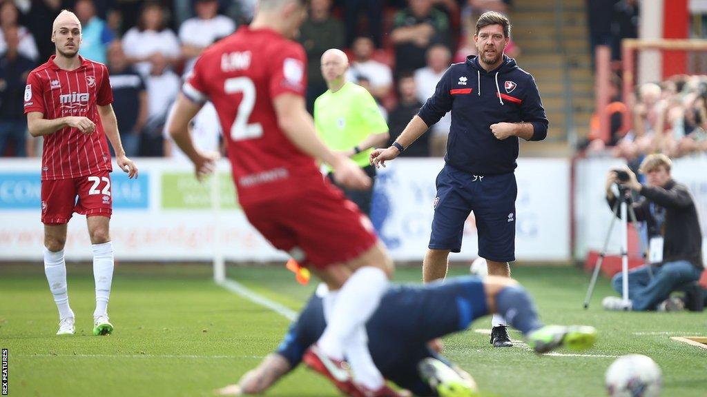 Darrell Clarke (right) looks on as a Cheltenham player tries to win the ball from Derby