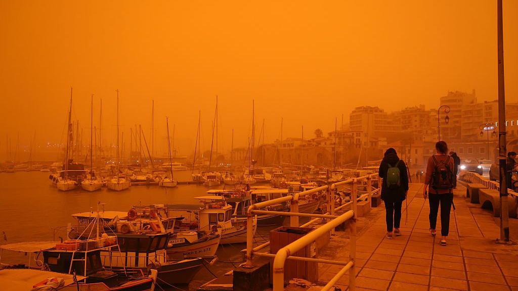 saharan dust storm orange sky by sea.