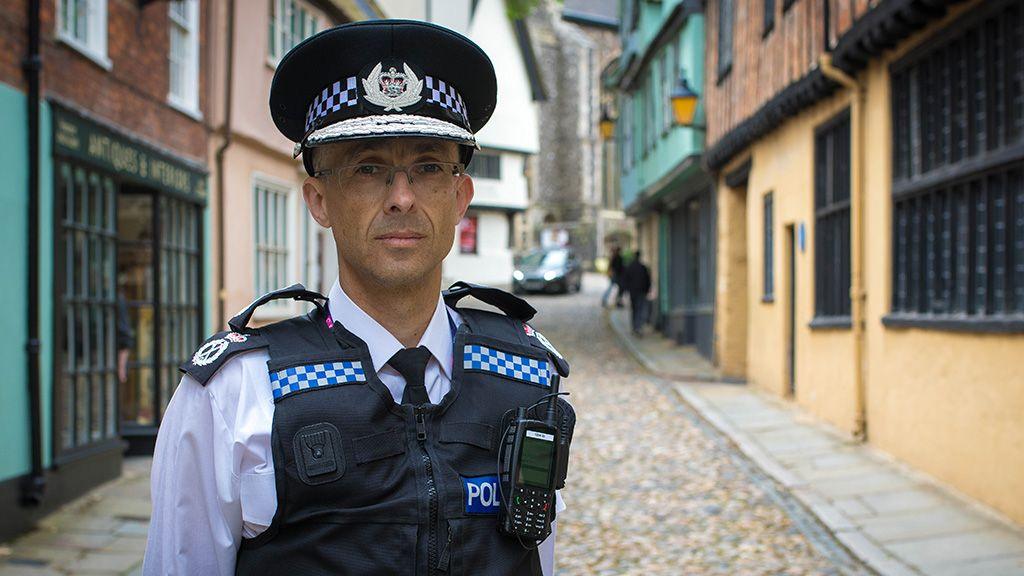 Norfolk Chief Constable Paul Sanford stands in uniform on cobbled street in Norwich