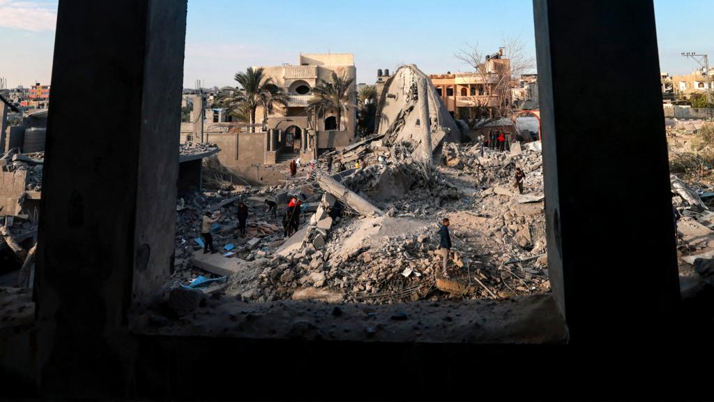 Palestinians stand amidst the rubble of buildings destroyed in Israeli bombardment in Rafah in the southern Gaza Strip on 25 January 2024