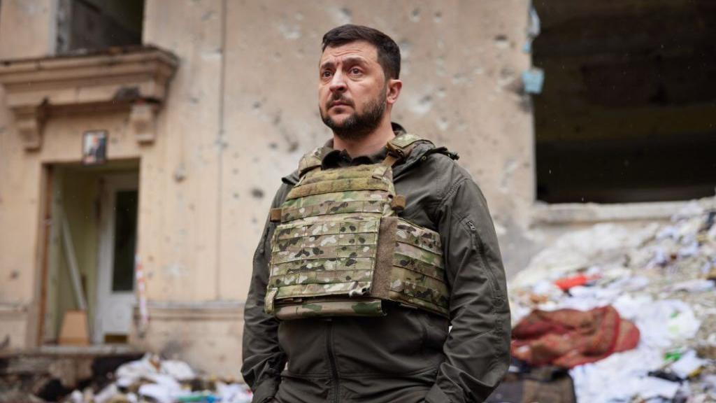 President Zelensky stood in front of a bombed-out building. 