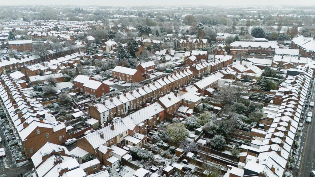 An aerial shots of dozens of houses in Warwick covered in snow stretching off to the distance