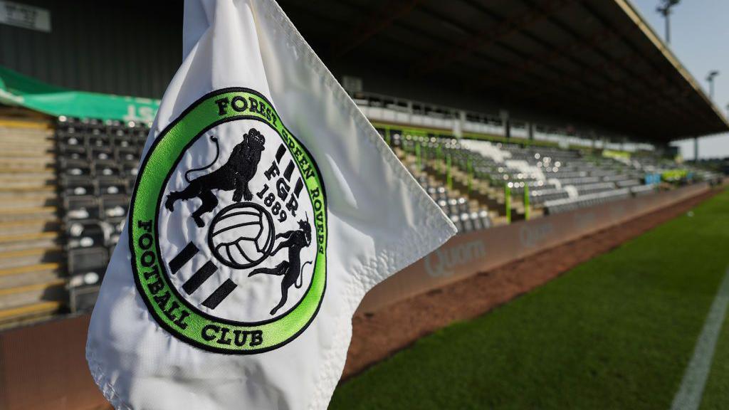 A shot of the corner flag with the Forest Green Rovers badge on it with the New Lawn stadium in the background