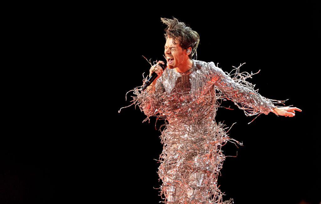 Singer Harry Styles performing in a sparkly silver outfit.