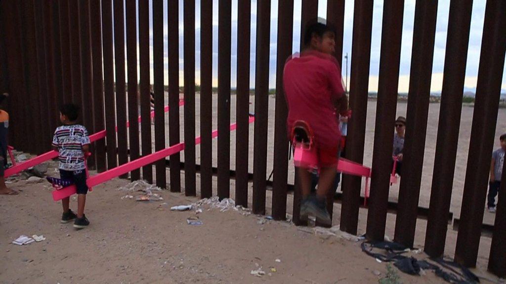 Children play on seesaws on the US border