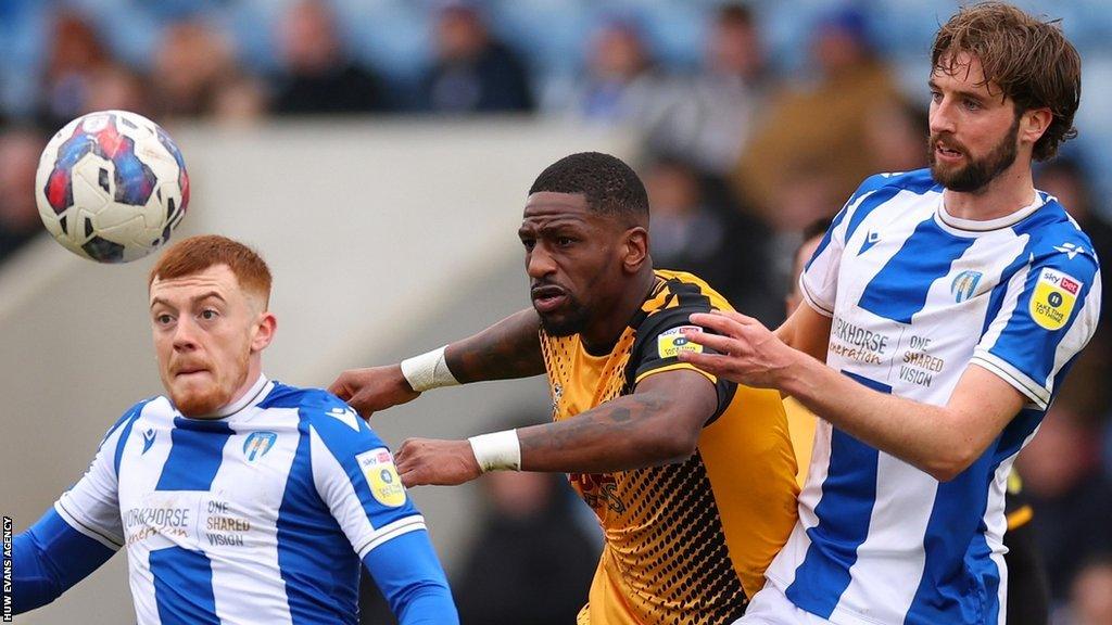 Omar Bogle (C) of Newport County is man-marked by Colchester's Arthur Read (L) and Fiacre Kelleher (R)