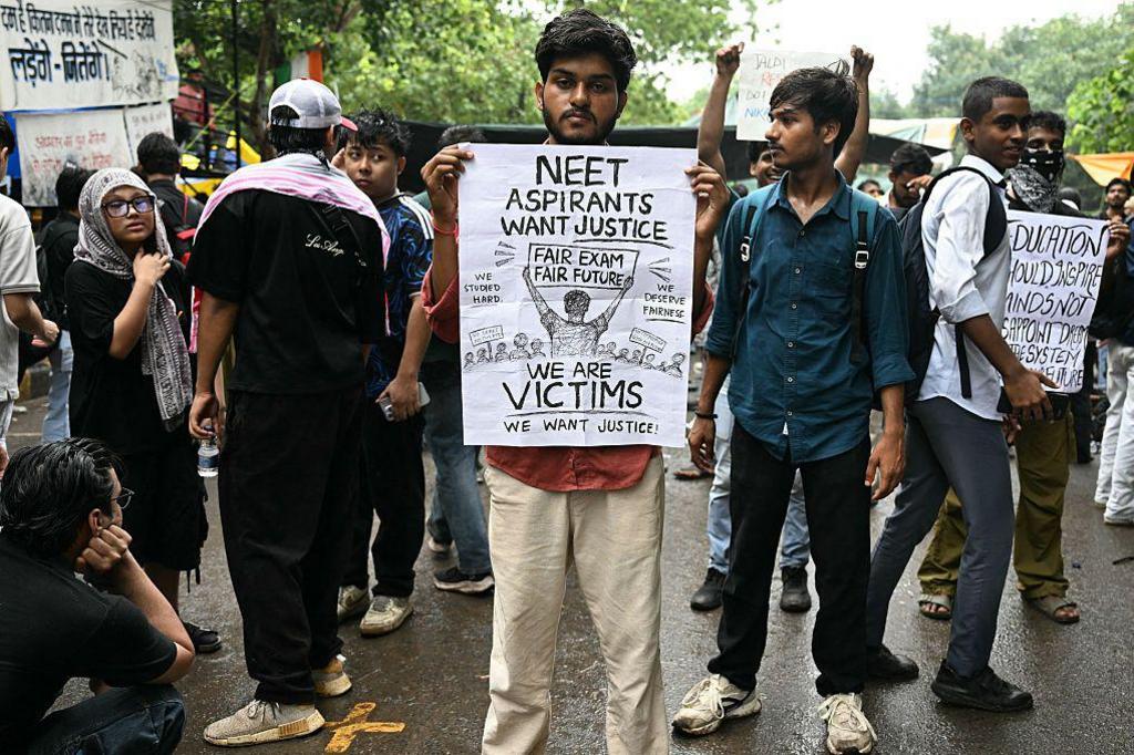 A Cockroach Janta Party (CJP) supporter holds a placard at Jantar Mantar in New Delhi on July 22, 2026 during the ongoing protest to demand the resignation of India's Education Minister Dharmendra Pradhan over alleged NEET exam irregularities. 