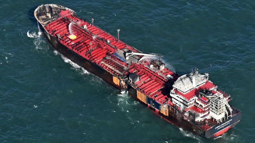 An aerial view of an oil tanker. It has a hole in the side after a collision with a cargo ship.