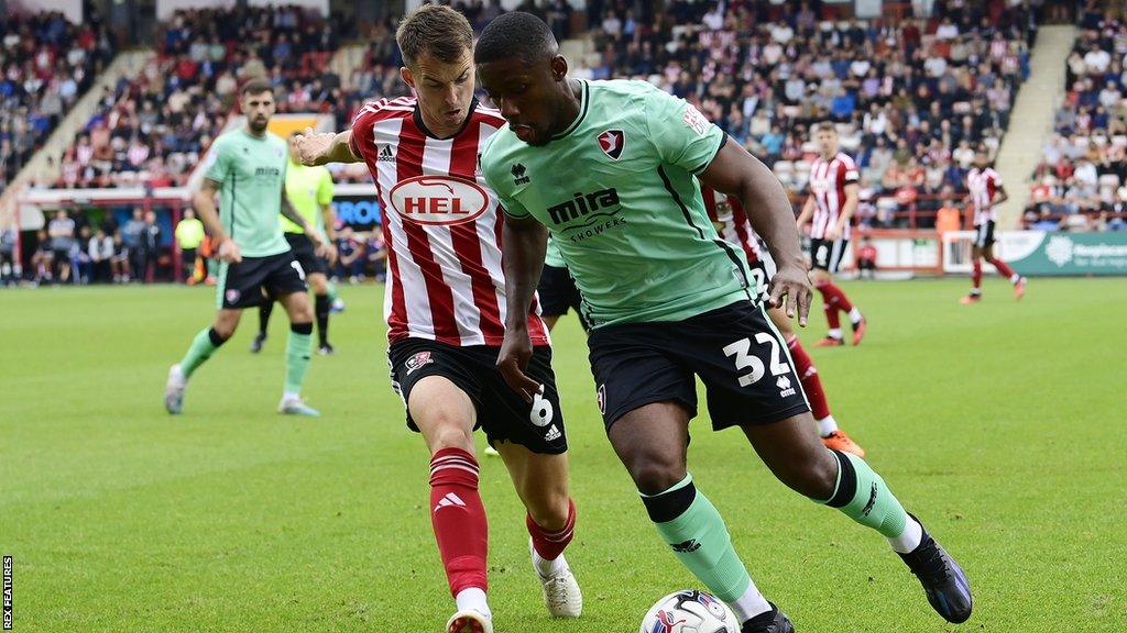 Jovan Malcolm (right) with the ball for Cheltenham against Exter