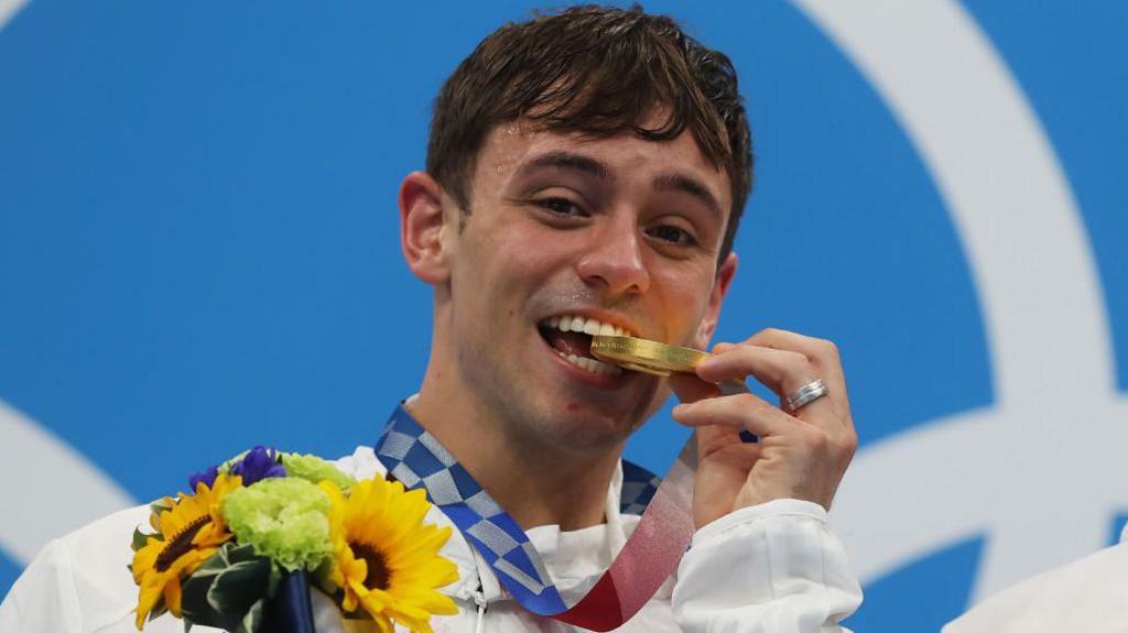 Tom Daley biting his gold medal in Tokyo