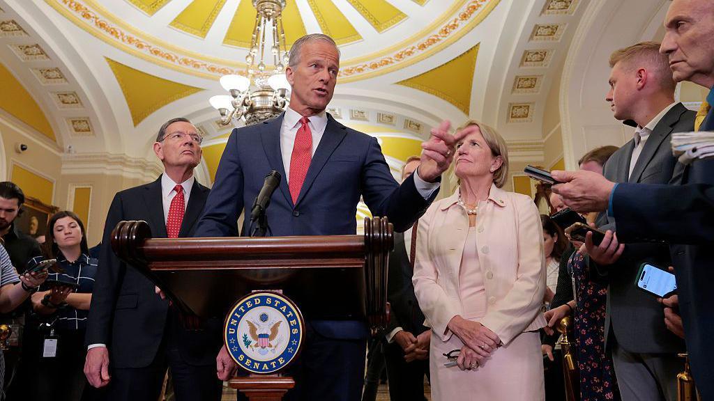 Senate Majority Leader John Thune speaks to reporters at the US Capitol. He is accompanied by other senators and speaking behind a podium with the Senate logo. 