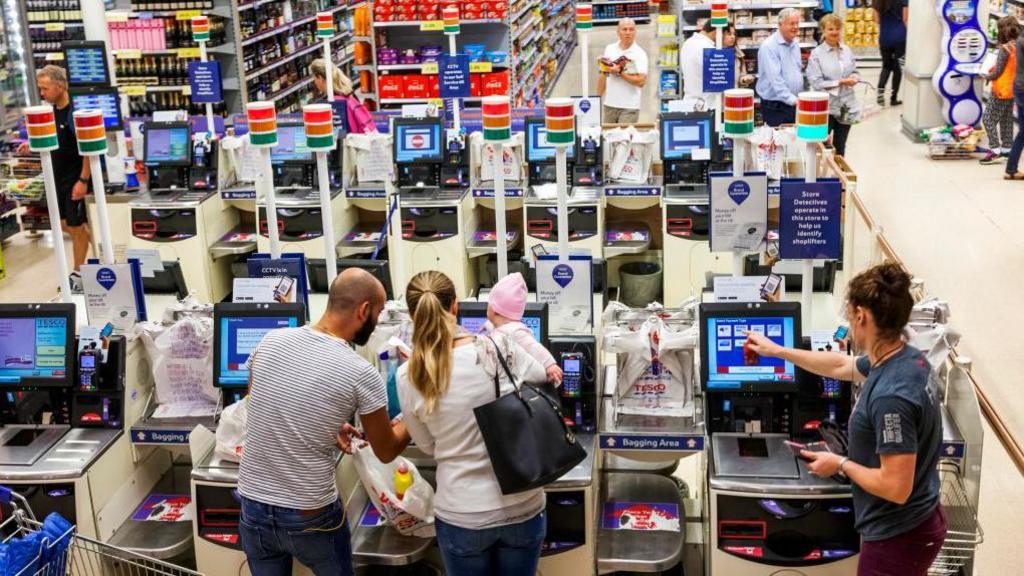 People use self-service checkouts in a large Tesco store