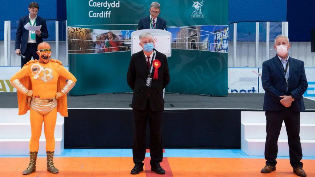 Then First Minister of Wales Mark Drakeford (centre) looks on after winning the Cardiff West constituency as candidate Captain Beany (L) looks on at the Cardiff House of Sport on May 7, 2021